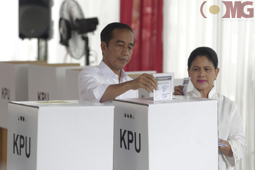 Capres nomor urut 01 Jokowi didampingi istrinya Iriana Joko Widodo saat memasuki surat suara ke kotak suara.